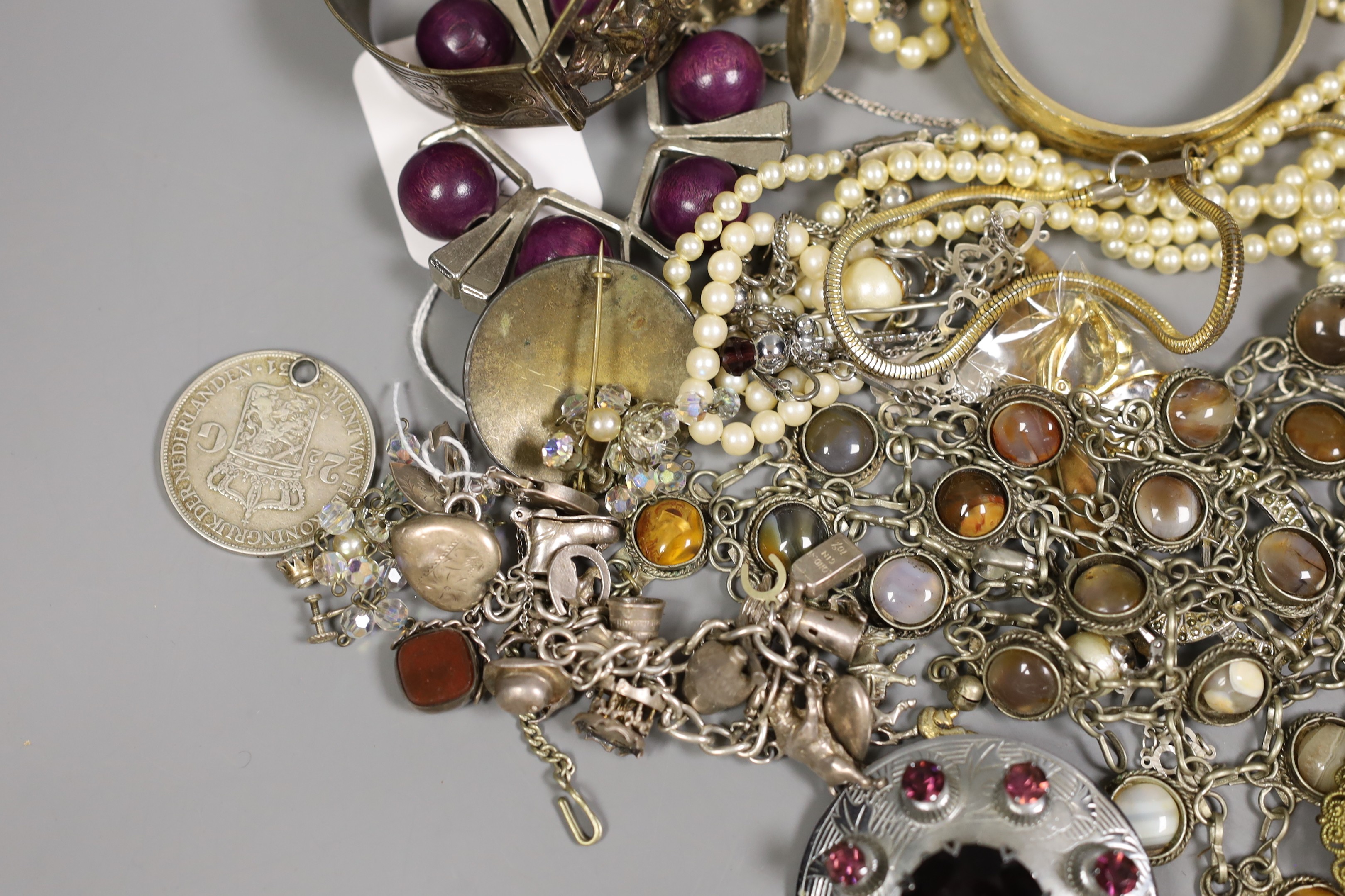 Assorted costume jewellery including a silver charm bracelet, hung with various charms including merry-go-round and bull.